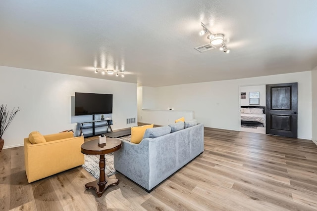 living room with light wood-type flooring and track lighting