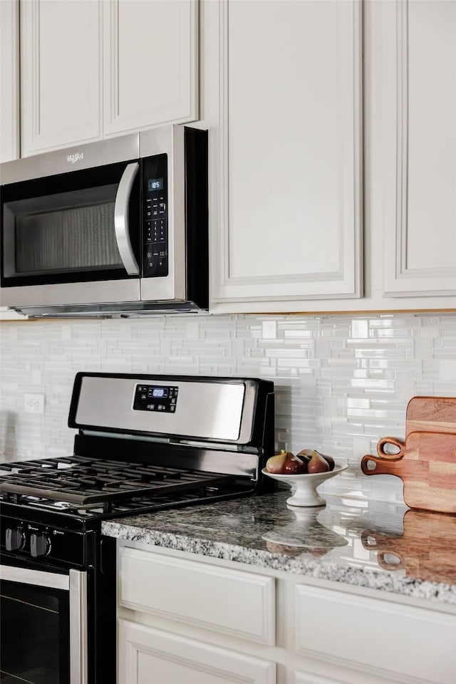 kitchen featuring stainless steel appliances, light stone countertops, and white cabinets