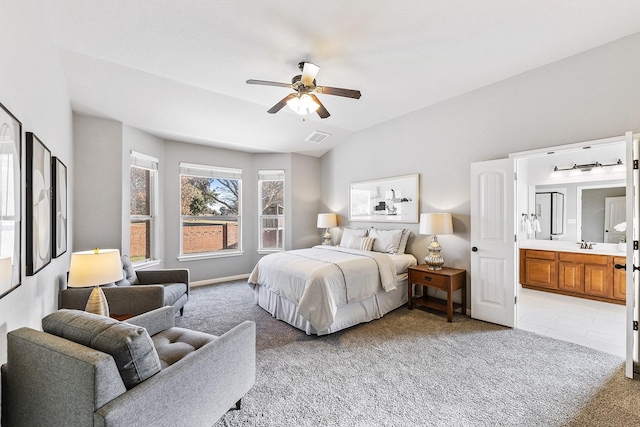 carpeted bedroom featuring lofted ceiling, ensuite bath, ceiling fan, and sink