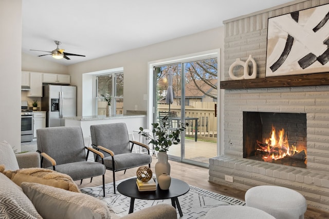 living room featuring ceiling fan, light hardwood / wood-style flooring, vaulted ceiling, and a fireplace