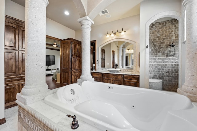 bathroom with tiled tub, vanity, and ornate columns