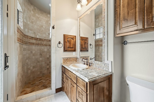 bathroom with tile patterned flooring, toilet, vanity, a shower, and decorative backsplash