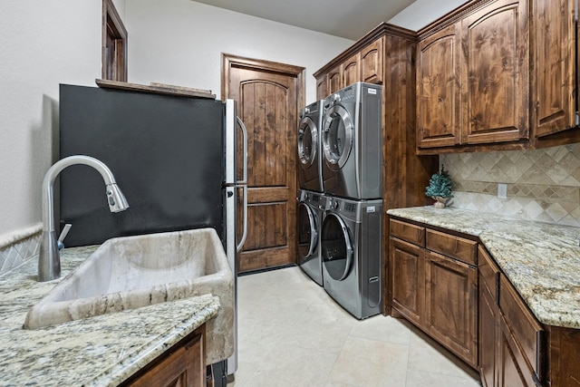 washroom featuring sink, cabinets, stacked washer / drying machine, and light tile patterned floors