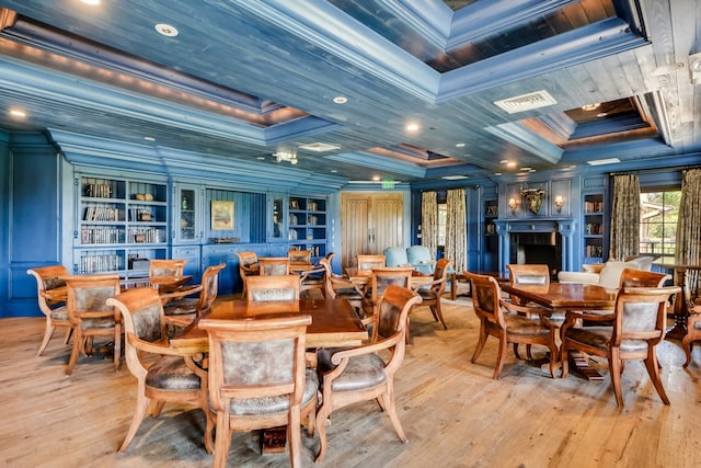 dining area featuring coffered ceiling, crown molding, light wood-type flooring, and built in features