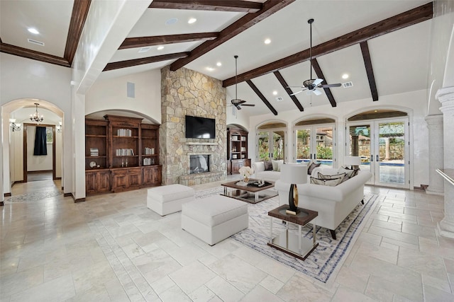 living room with french doors, high vaulted ceiling, beam ceiling, ceiling fan with notable chandelier, and a stone fireplace