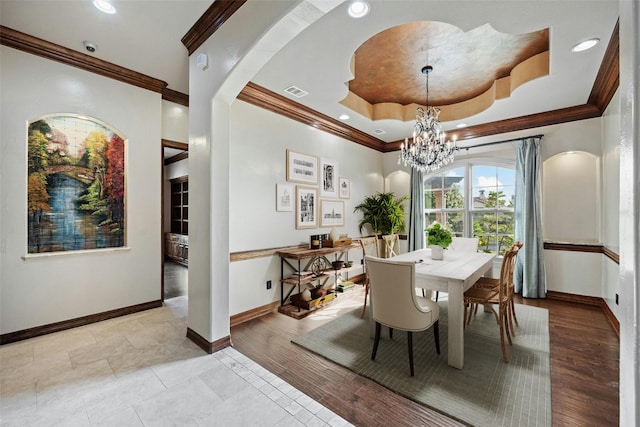 dining area with a notable chandelier, a tray ceiling, and crown molding