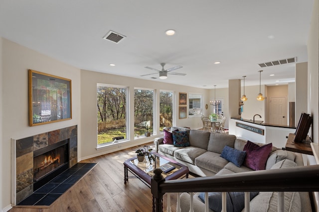 living room with sink, a fireplace, ceiling fan, and dark wood-type flooring