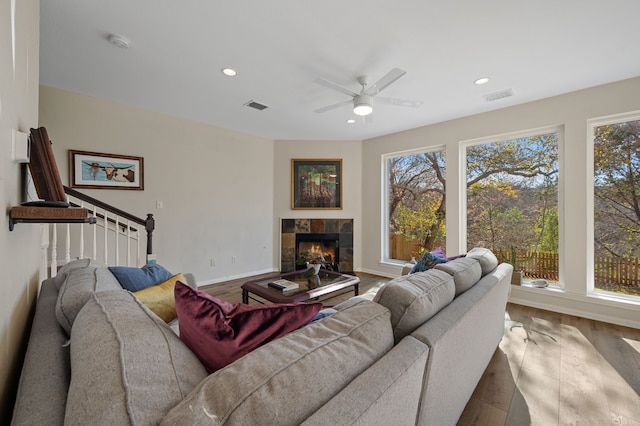 living room featuring a tile fireplace, ceiling fan, and hardwood / wood-style floors