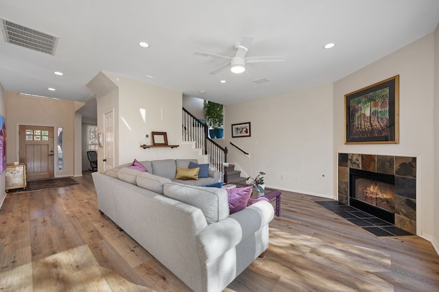 living room featuring a tiled fireplace, ceiling fan, and hardwood / wood-style flooring