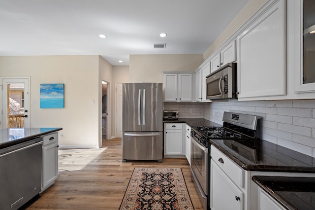 kitchen with appliances with stainless steel finishes, white cabinetry, and dark stone countertops