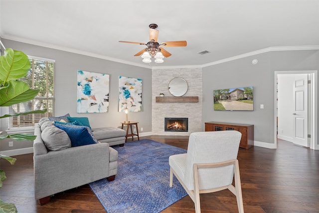 living room featuring ceiling fan, dark hardwood / wood-style flooring, a stone fireplace, and ornamental molding