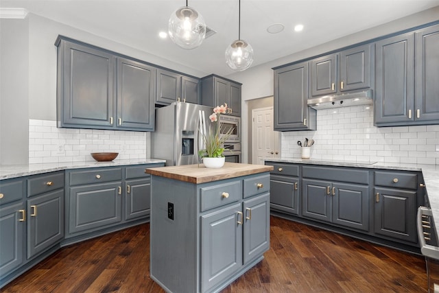 kitchen with gray cabinets, appliances with stainless steel finishes, a center island, light stone countertops, and tasteful backsplash