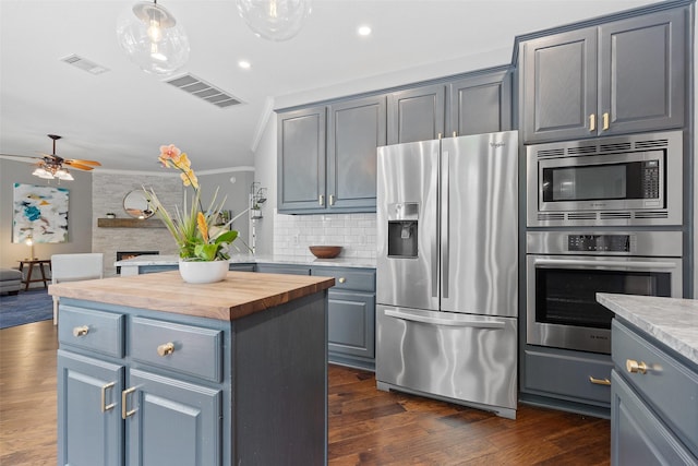 kitchen featuring a center island, wooden counters, backsplash, appliances with stainless steel finishes, and ornamental molding