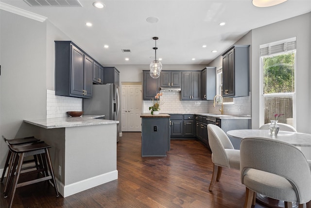 kitchen featuring light stone counters, dark hardwood / wood-style floors, decorative light fixtures, gray cabinetry, and appliances with stainless steel finishes