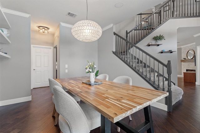 dining room featuring ornamental molding, a stone fireplace, an inviting chandelier, and dark hardwood / wood-style floors