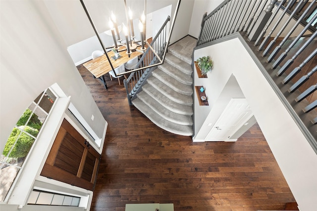 stairs with a high ceiling, hardwood / wood-style flooring, and a notable chandelier