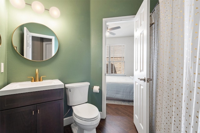 bathroom with toilet, curtained shower, hardwood / wood-style floors, ceiling fan, and vanity