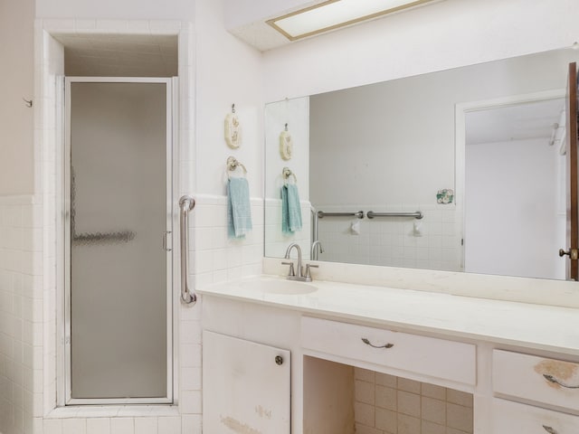 bathroom featuring tile walls, a shower with door, and vanity