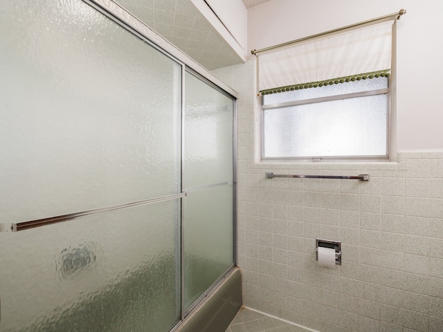 bathroom with tile walls and enclosed tub / shower combo