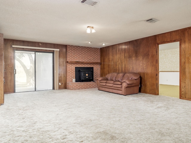 living room with carpet flooring, a textured ceiling, wood walls, and a wood stove