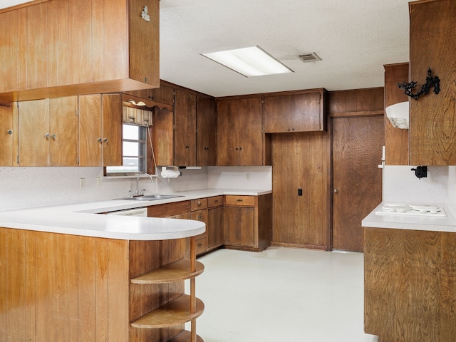 kitchen featuring sink, decorative backsplash, a textured ceiling, and kitchen peninsula