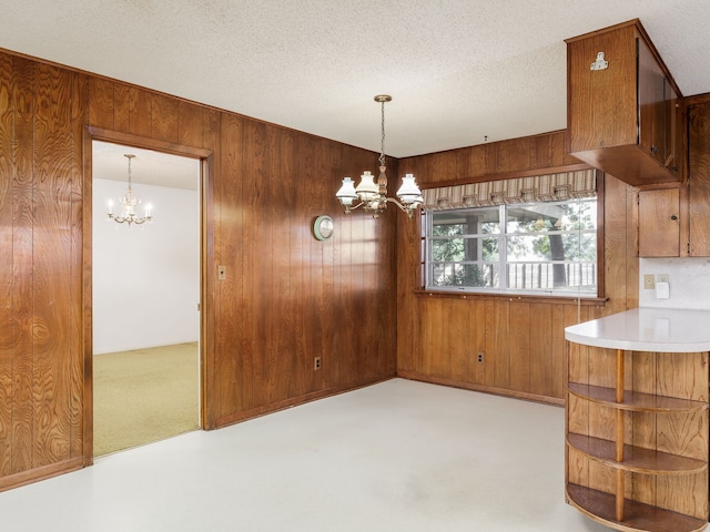 dining room featuring wood walls, a textured ceiling, and a notable chandelier