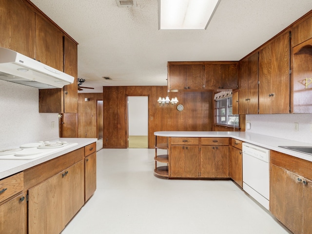 kitchen with white appliances, wooden walls, a textured ceiling, and ceiling fan with notable chandelier