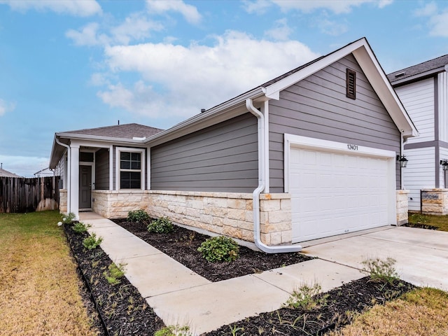 ranch-style house with an attached garage, fence, stone siding, driveway, and a front yard