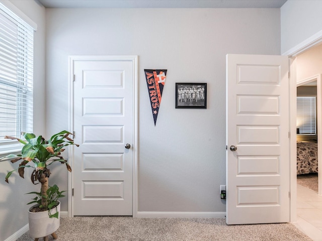 corridor featuring light colored carpet and baseboards