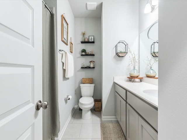 bathroom featuring baseboards, vanity, toilet, and tile patterned floors