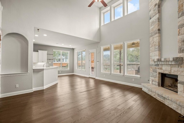 3816 Tango Ct, Leander, TX 78641 - unfurnished living room with a ceiling fan, a stone fireplace, dark wood finished floors, and a high ceiling