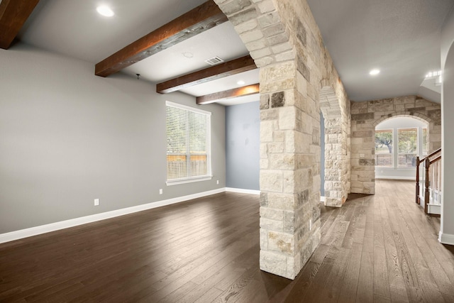 interior space featuring ornate columns, beamed ceiling, and dark hardwood / wood-style floors