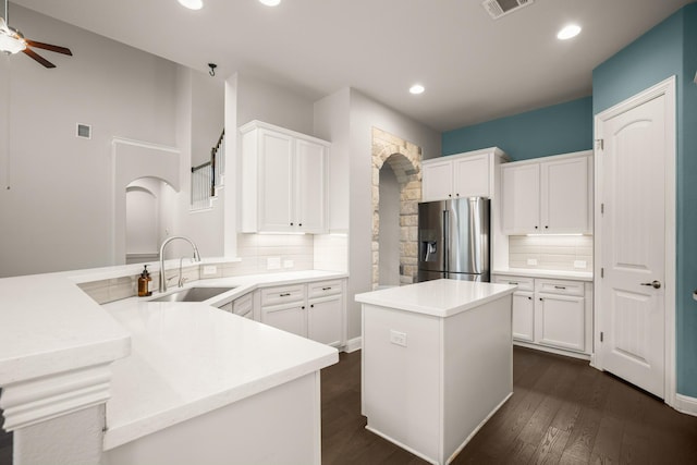 kitchen with a kitchen island, stainless steel fridge, white cabinets, and kitchen peninsula