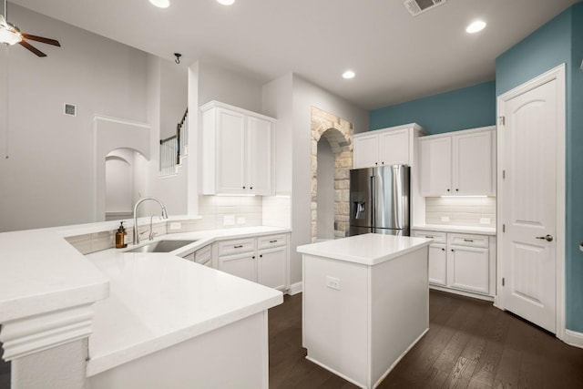 3816 Tango Ct, Leander, TX 78641 - kitchen with stainless steel fridge, arched walkways, a peninsula, tasteful backsplash, and recessed lighting