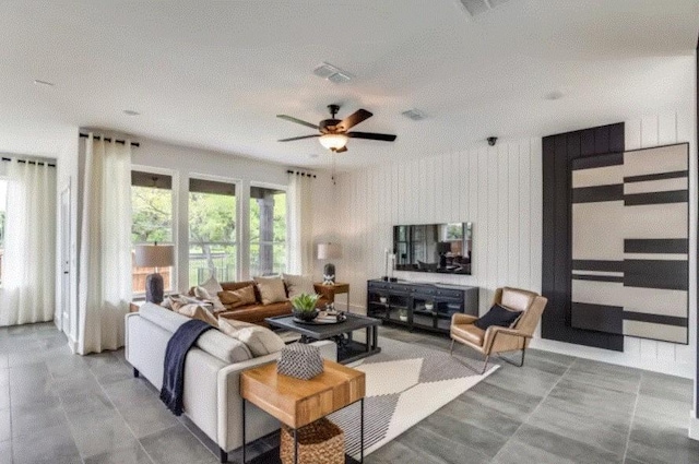 living room featuring wood walls, ceiling fan, and plenty of natural light