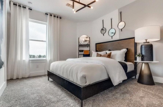 bedroom with an inviting chandelier, multiple windows, and light colored carpet