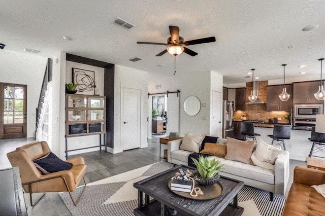 living room featuring ceiling fan and a barn door