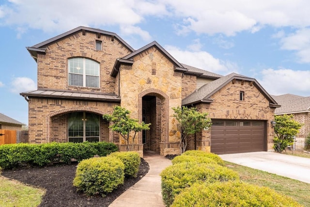 974 Clear Springs Holw, Buda, TX 78610 - view of front of home with brick siding, concrete driveway, a standing seam roof, and a garage