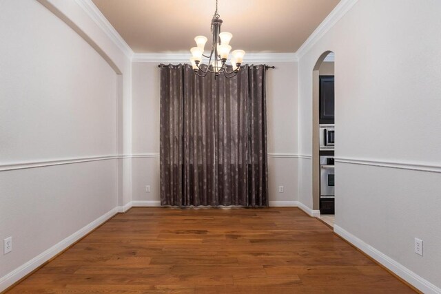 974 Clear Springs Holw, Buda, TX 78610 - unfurnished dining area featuring arched walkways, a chandelier, crown molding, wood finished floors, and baseboards