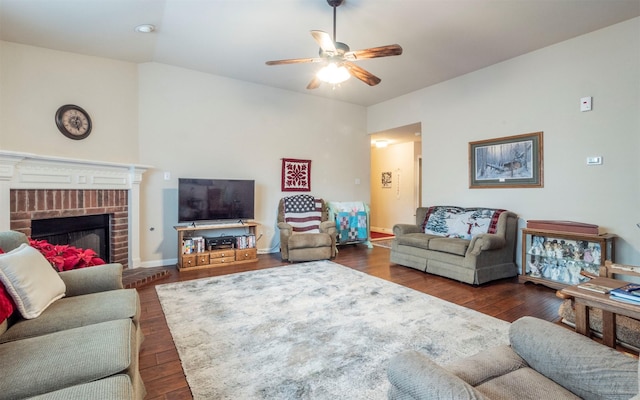 living room with a brick fireplace, ceiling fan, and dark hardwood / wood-style floors