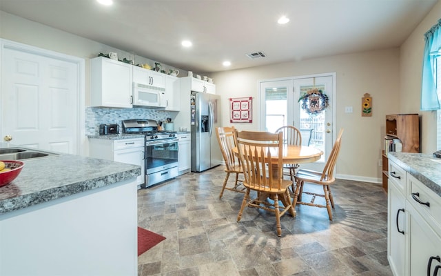 kitchen featuring appliances with stainless steel finishes, white cabinets, sink, and decorative backsplash