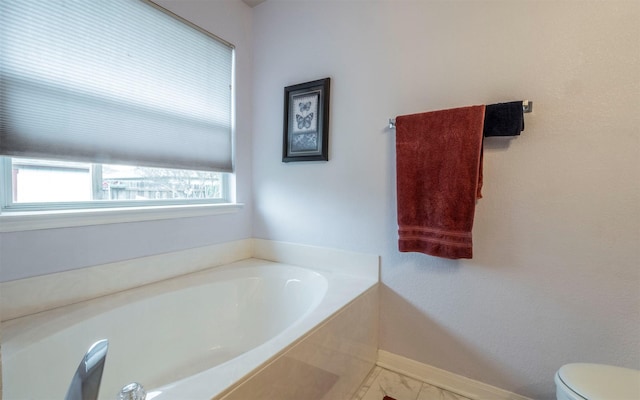 bathroom featuring toilet, tile patterned floors, and a tub to relax in