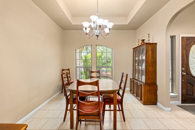 dining room with light tile patterned floors, a tray ceiling, and a notable chandelier