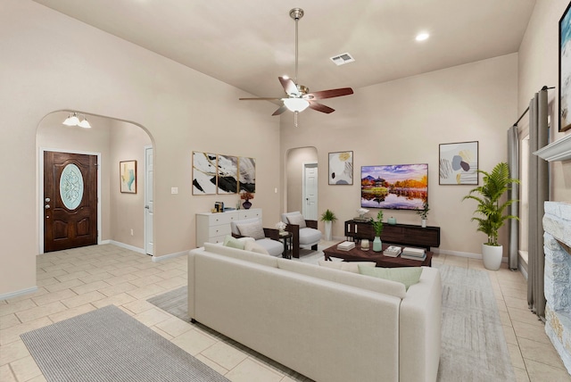 living room featuring ceiling fan with notable chandelier, high vaulted ceiling, and light tile patterned flooring