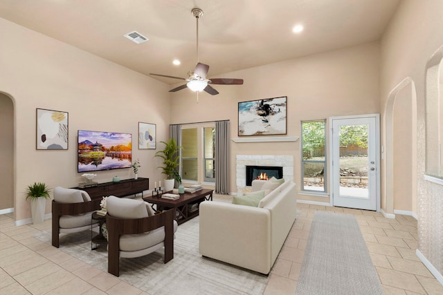 living room with ceiling fan, a towering ceiling, and light tile patterned flooring