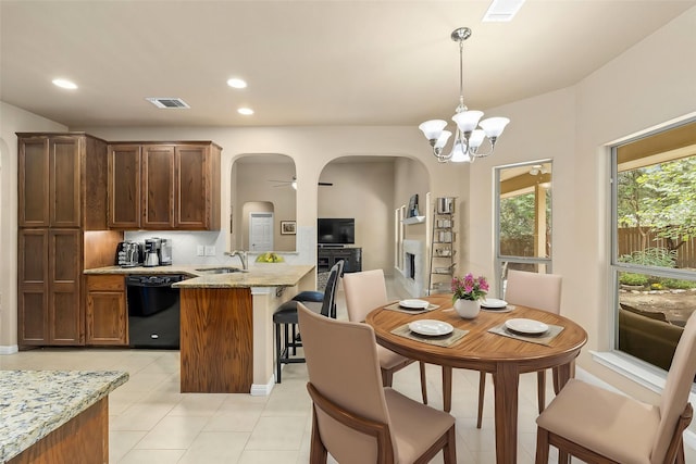 kitchen featuring sink, dishwasher, light stone counters, ceiling fan with notable chandelier, and pendant lighting