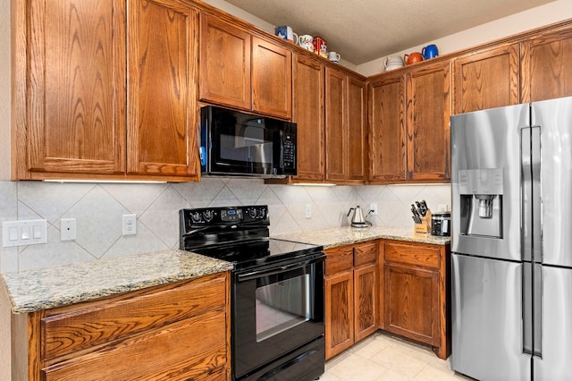 kitchen featuring black appliances, backsplash, light stone countertops, and a textured ceiling