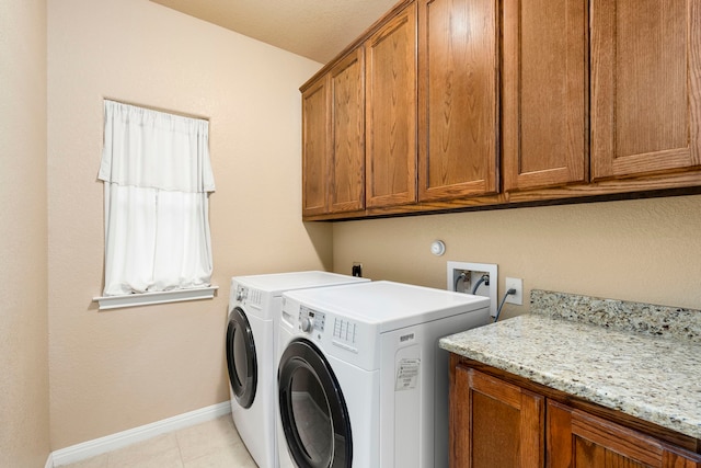 laundry room featuring washer and dryer, cabinets, and light tile patterned floors