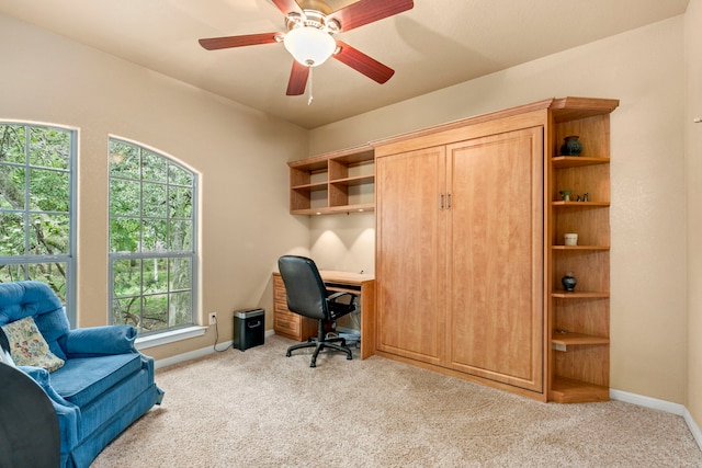 office space featuring a healthy amount of sunlight, ceiling fan, and light carpet