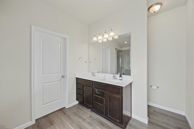 bathroom with a shower with shower door, hardwood / wood-style floors, and vanity